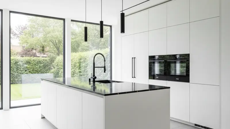Weiße Küche mit schwarzen Armaturen und schwarzer Marmor-Arbeitsplatte