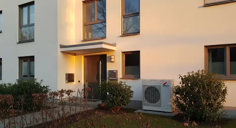 Wärmepumpen-Außeneinheit vor modernem Düsseldorfer Wohnhaus mit separatem Stromzähler