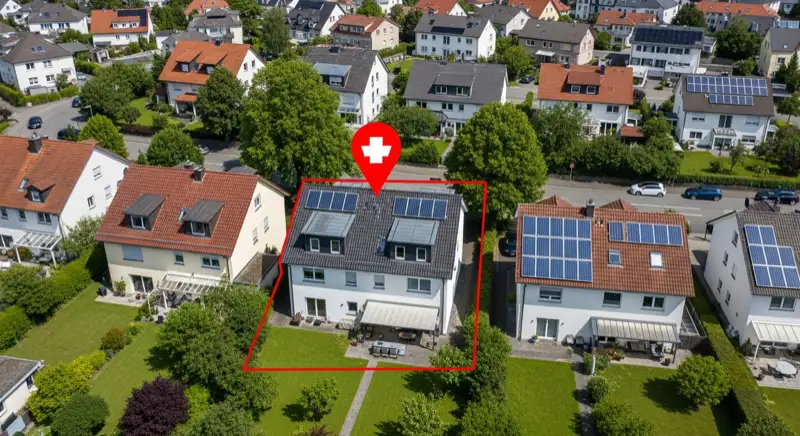 Aerial drone view of typical German residential neighborhood with mixed roof types, red and dark roof tiles, gardens visible, sunny day